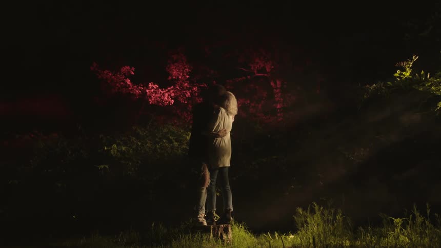 Man and woman kissing with trees in the background