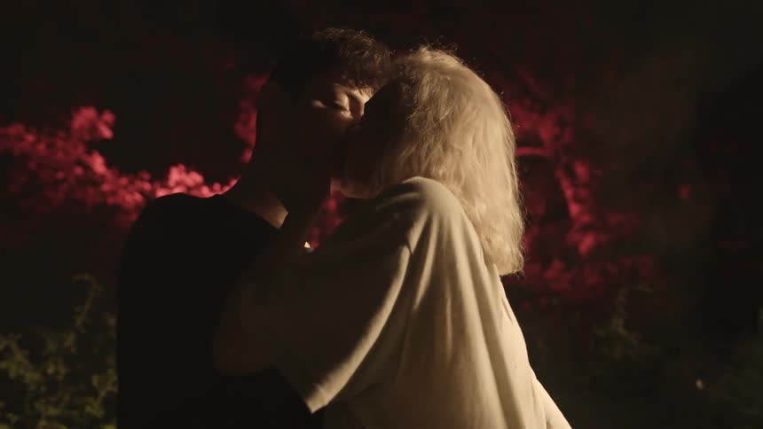 Man and woman kissing with trees in the background