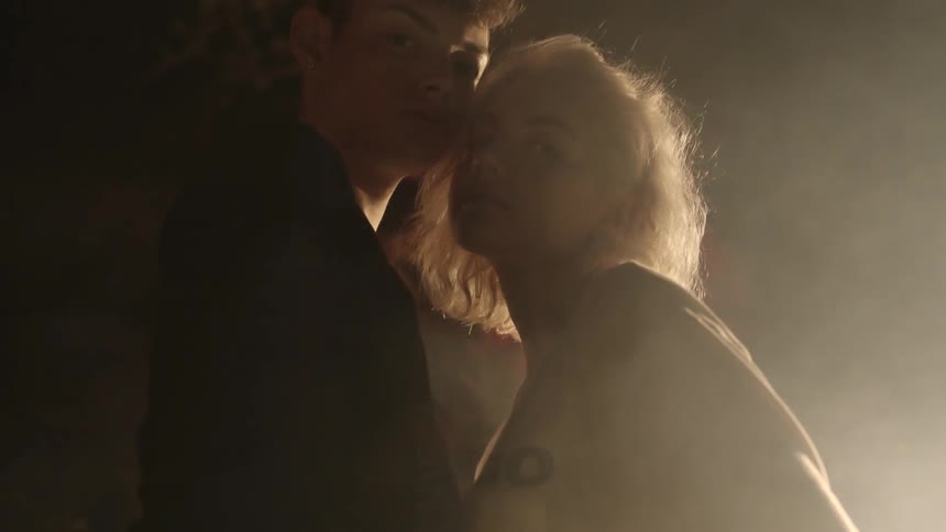 Man and woman standing together with dust blowing around them