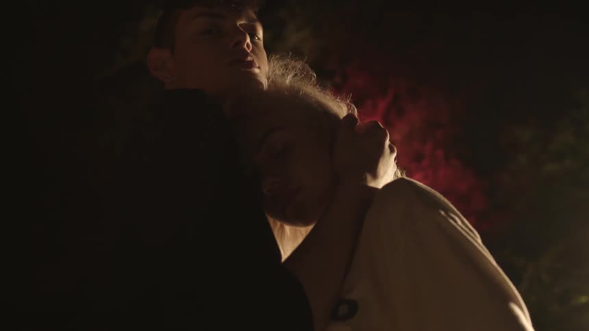 A woman leans against her boyfriend as he caresses her hair