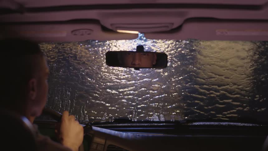 A man watches water run down his windshield