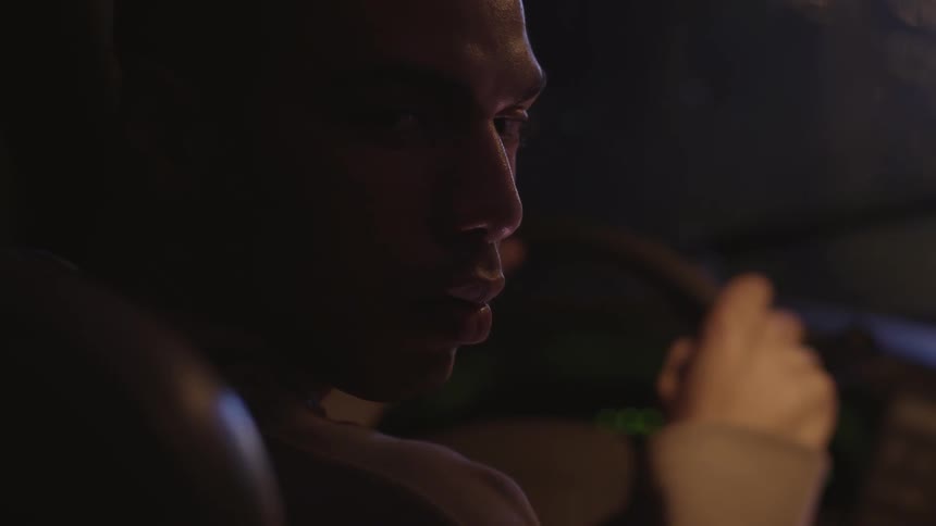 A man holds the steering wheel and stares into the back seat