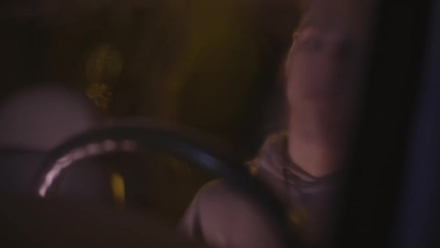A man sits in a car during a rainy night