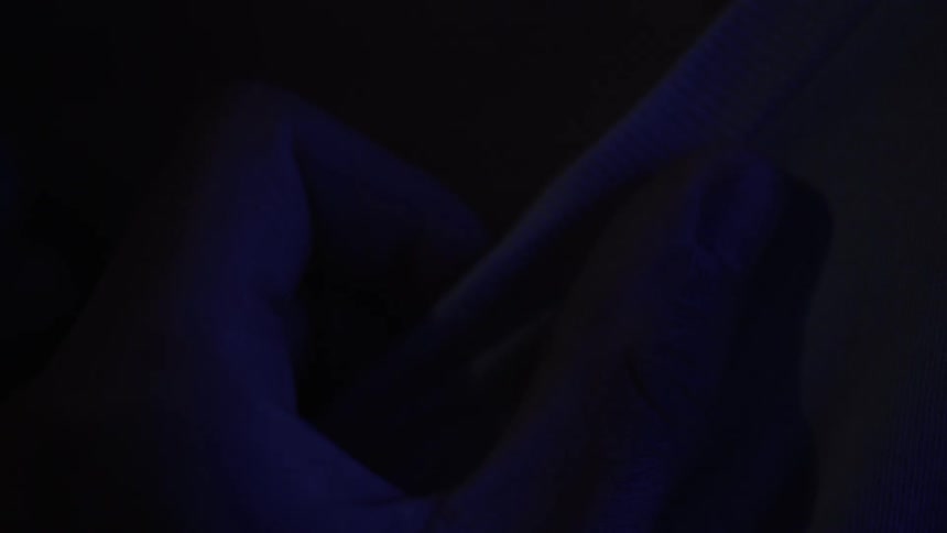 A hand rubs a t-shirt in in a dark area