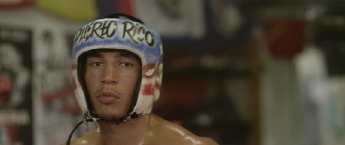 A boxer with helmet and gloves on moves around the camera