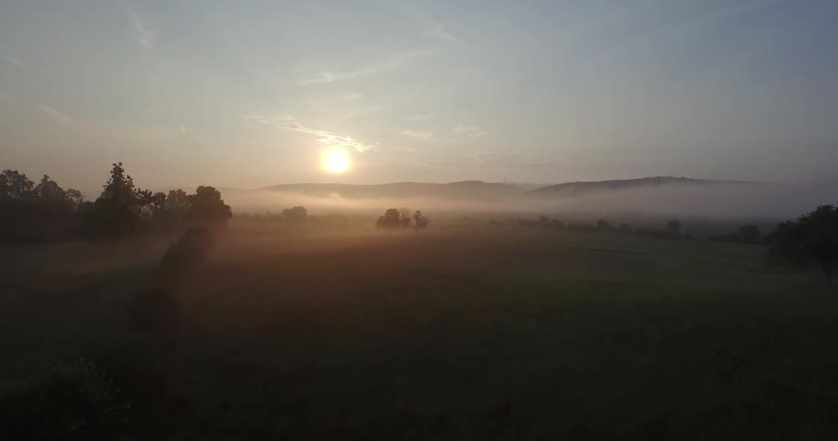 A foggy sunrise over an open field