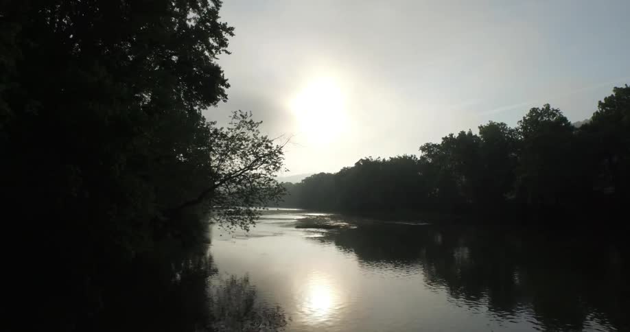 View of a cloudy sky over a river with trees on both sides
