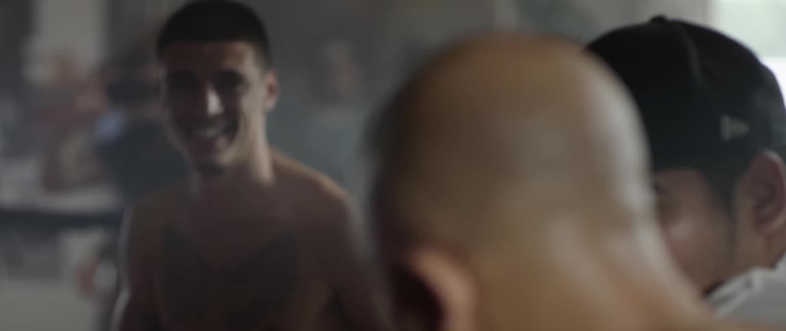 Shirtless man smiling and jumping in a boxing ring