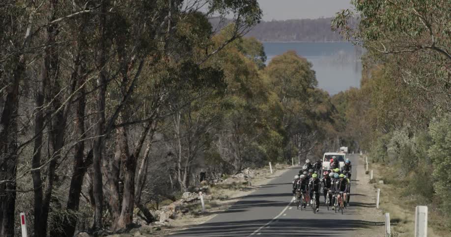 A group of cyclists ahead of a white truck