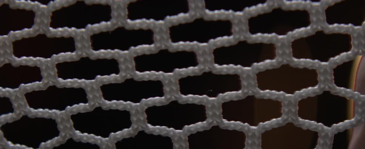 Hands pull at a webbed fabric and expand it