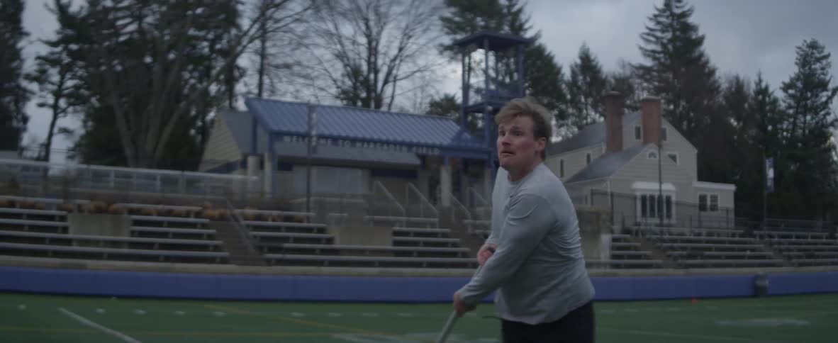 A man in a field swings a lacrosse stick