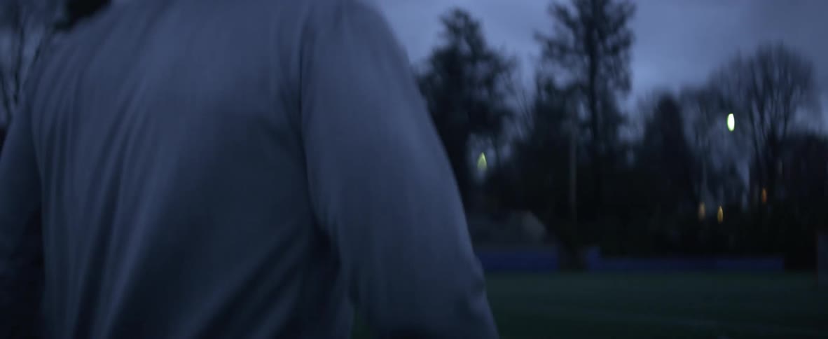 A man is holding a lacrosse stick and walking on a field