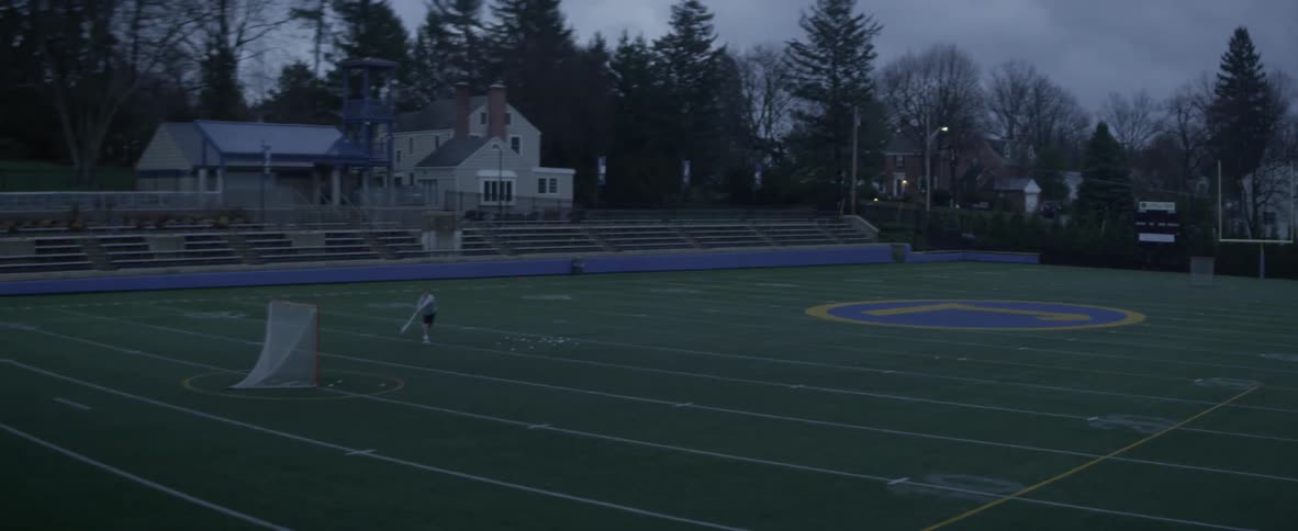 A man practices his lacrosse shot on a field