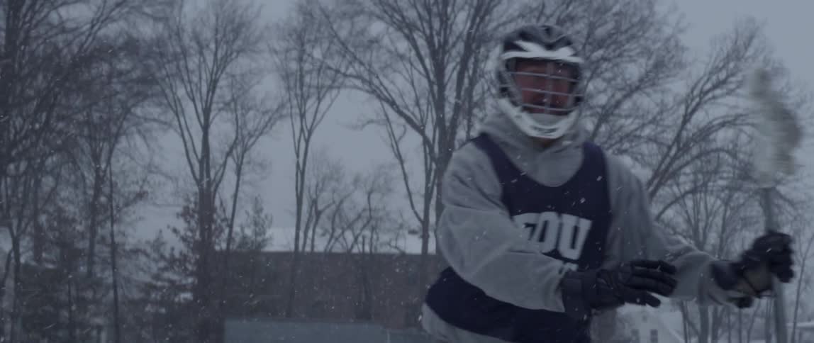 A man is playing lacrosse in the snow