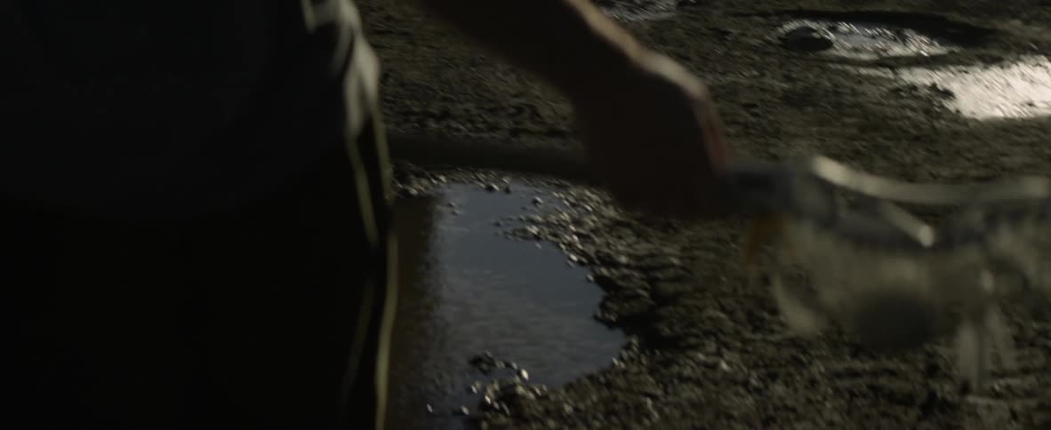 Person holds a lacrosse stick over a muddy puddle