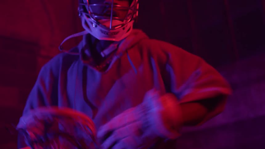 Person in a hooded sweatshirt practices lacrosse