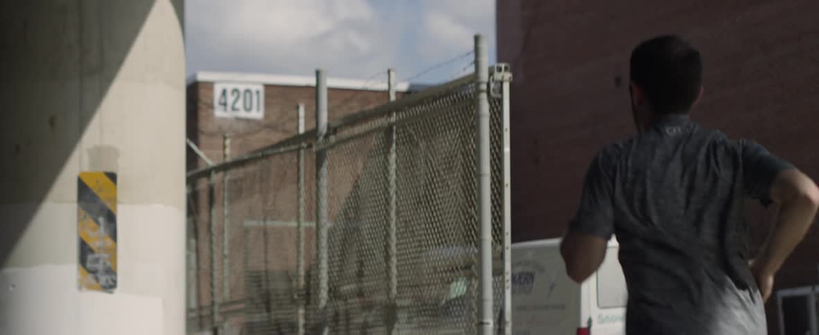 A man is jogging outside near some warehouses