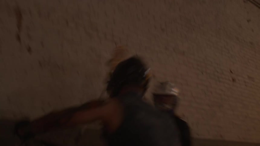Two people are playing lacrosse indoors
