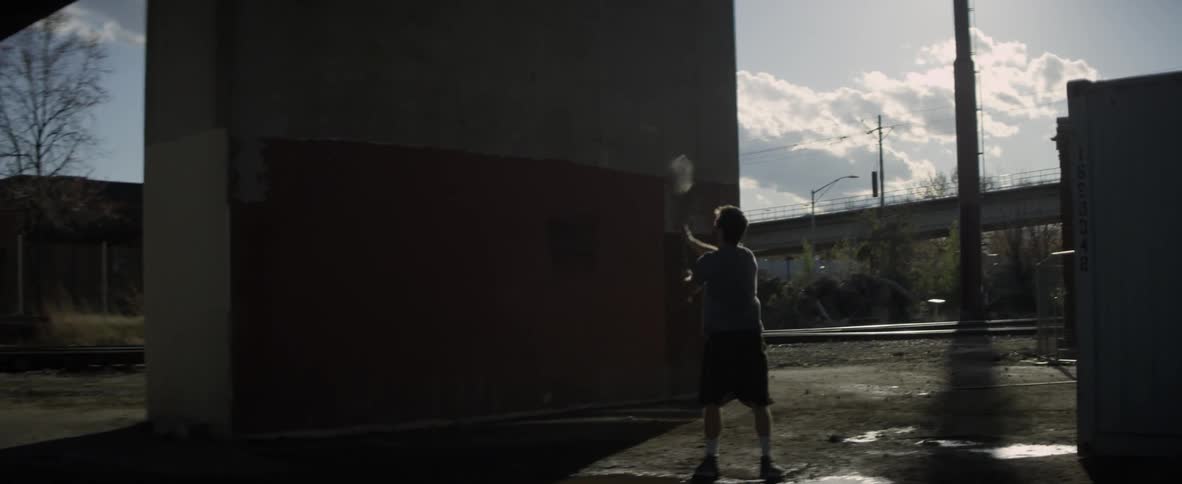 A man is tossing a ball at a wall with a lacrosse stick