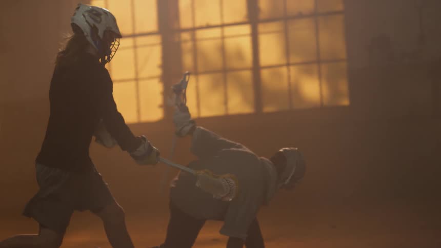 A lacrosse player almost falls after being hit with a stick