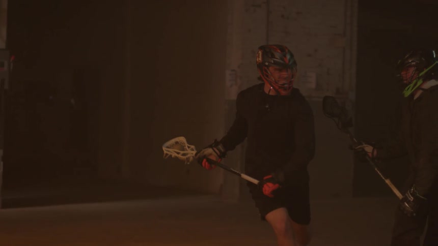 A lacrosse player swings his stick overhead