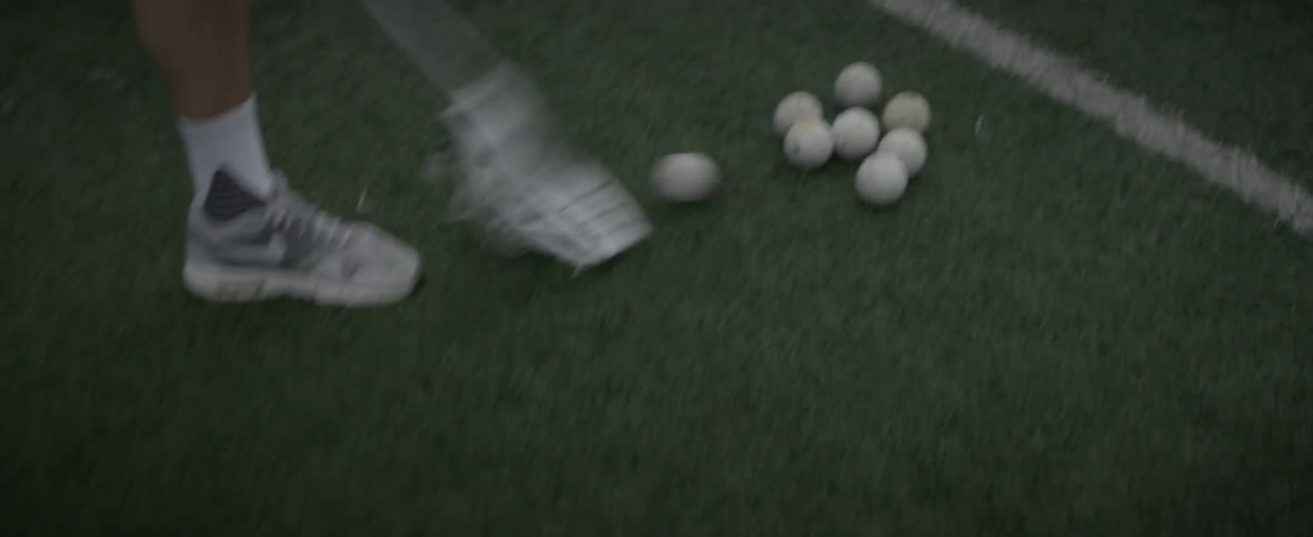 Man picks up ball on field with lacrosse net