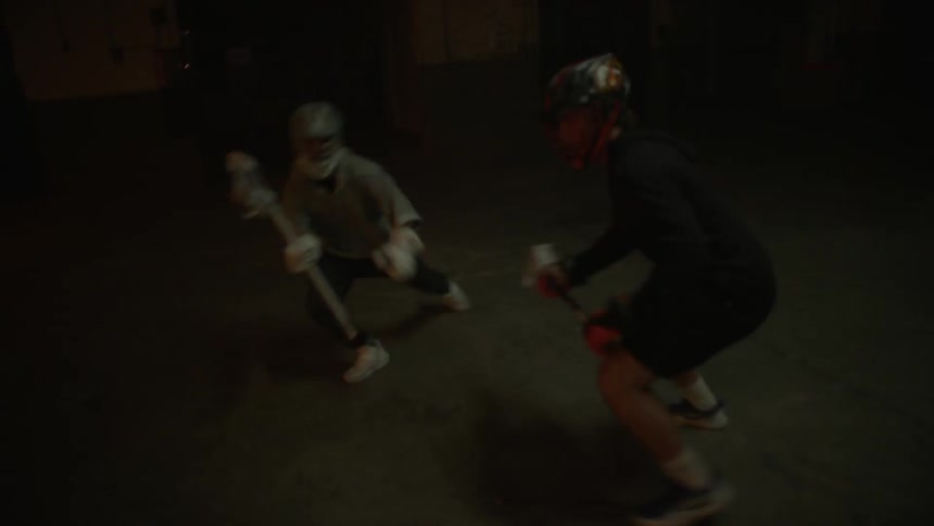 People with lacrosse nets and helmets running in dark abandoned building