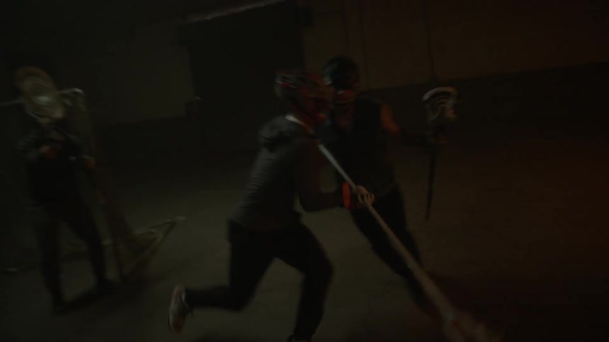 People playing lacrosse in a dark warehouse