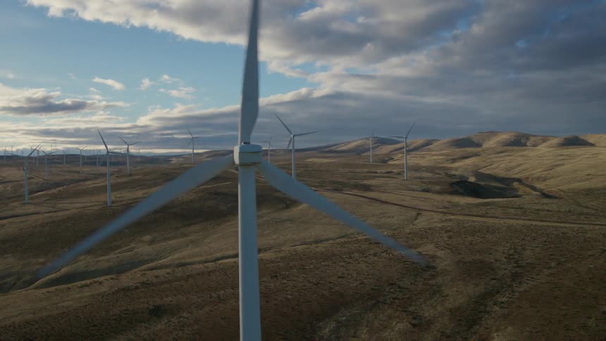 Wind turbines spinning along rugged foothills