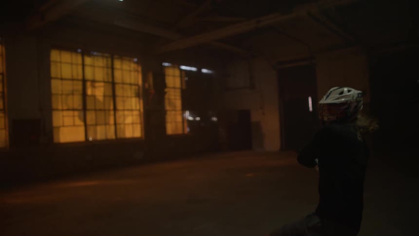 People are playing lacrosse in a dark gym