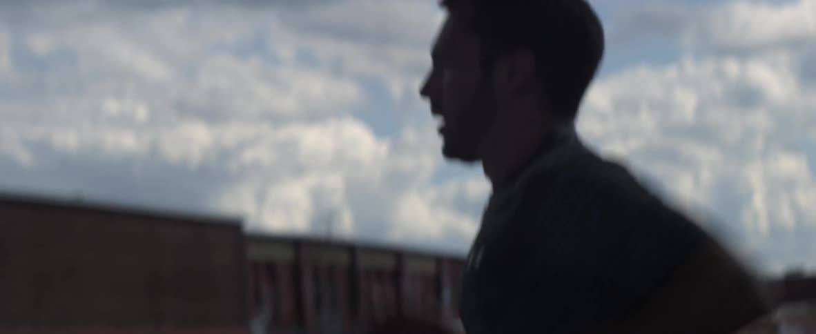 A man is jogging outside near some warehouses
