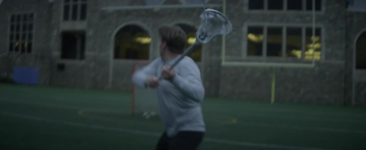 A man practices lacrosse in a field