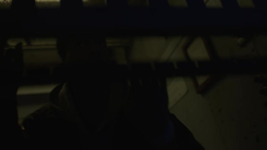 A man lowers a gate inside a dark warehouse