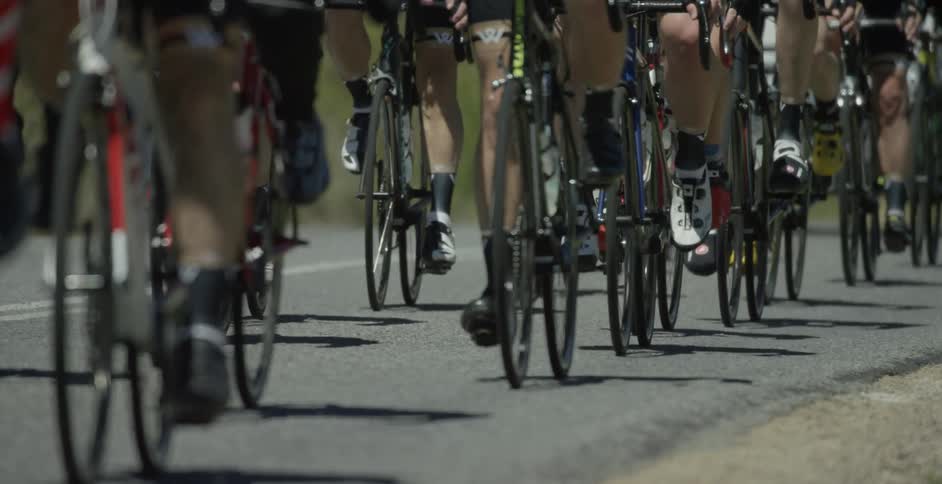 Cyclists in a peloton pedal their bikes