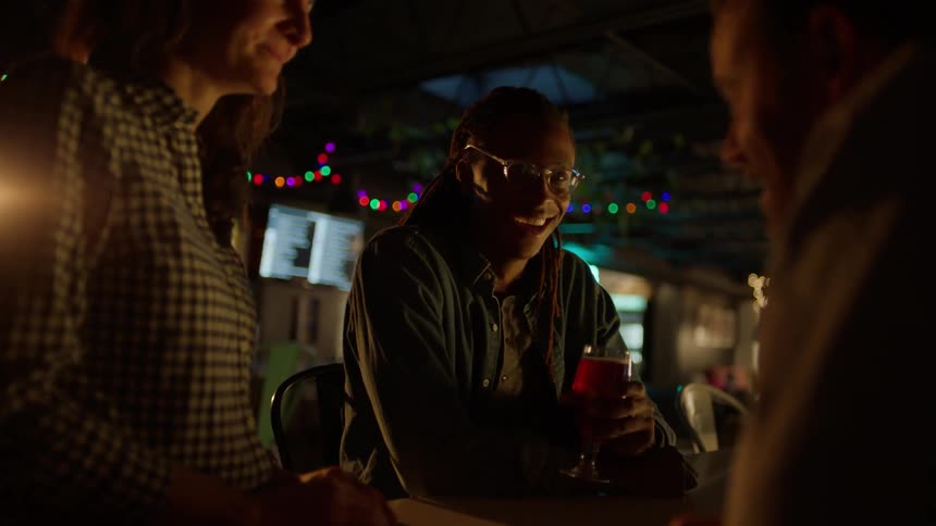 People talking and laughing in a dimly lit area of a bar