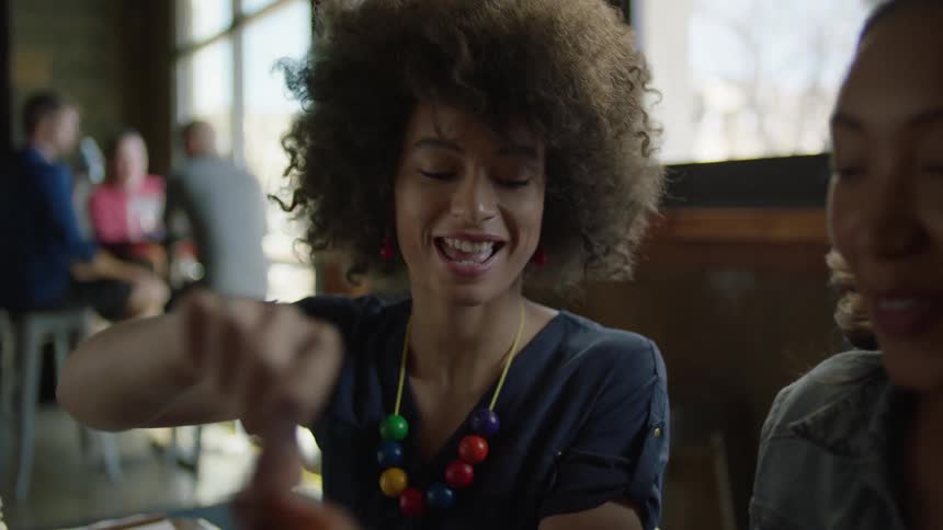 Two women laugh and talk while sitting at a restaurant