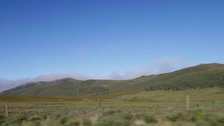 Sparse clouds appear from behind the hills