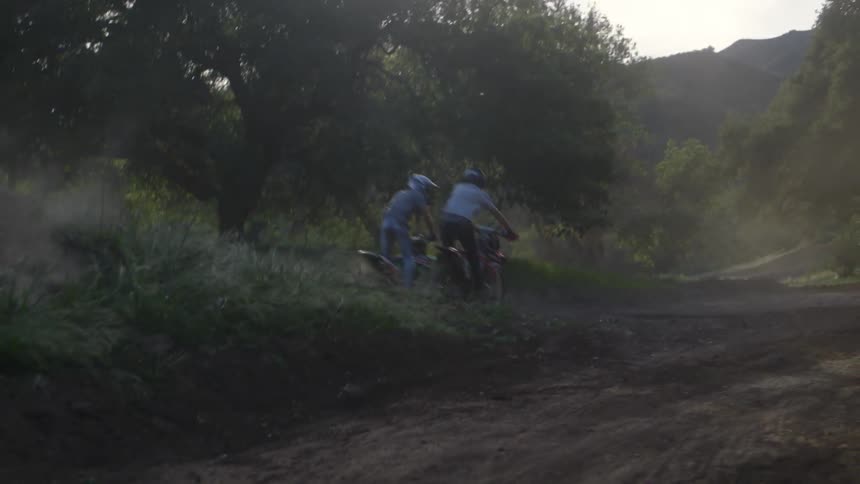 Two men ride dirt bikes