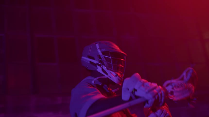 Person holding a lacrosse stick waves it around yelling