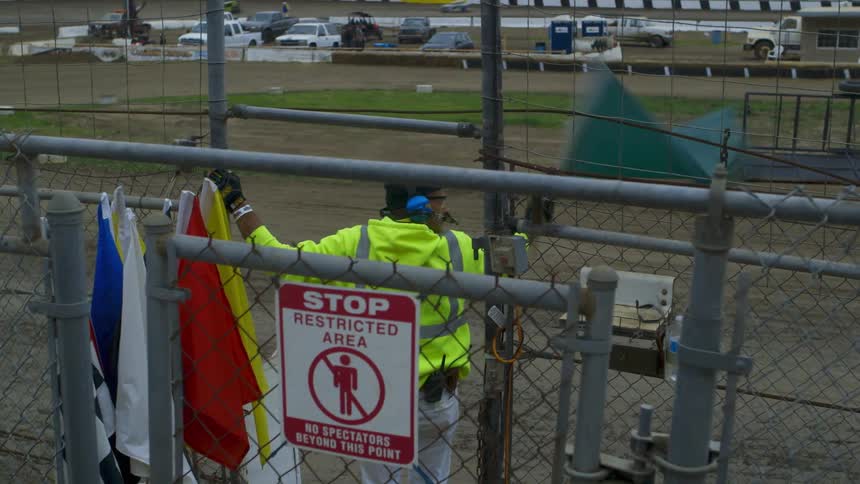 A flagman waves a flag at a car race