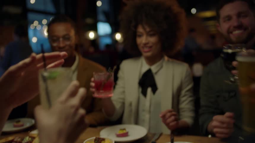 Friends toast and drink in a restaurant at night