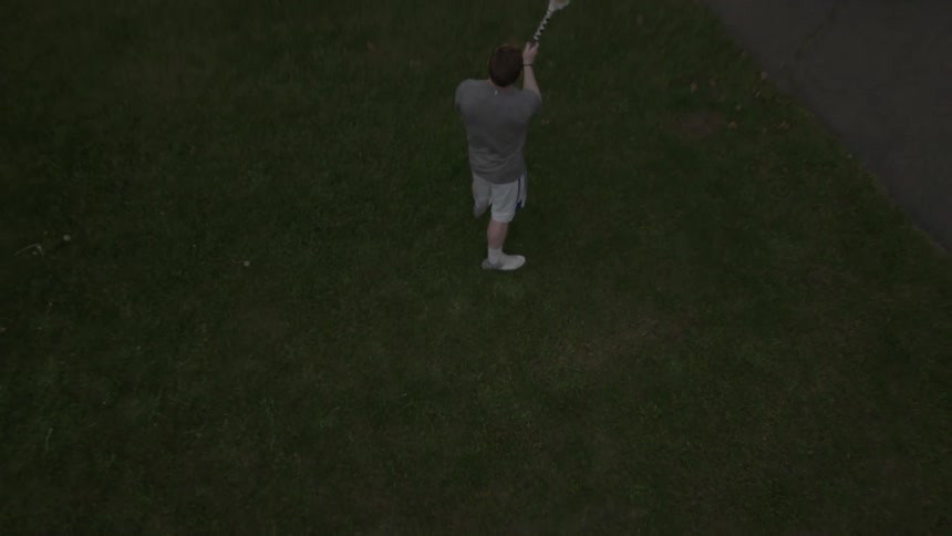 A man throws a lacrosse ball against a building