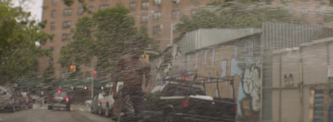 A male athlete runs through spraying water on a city street