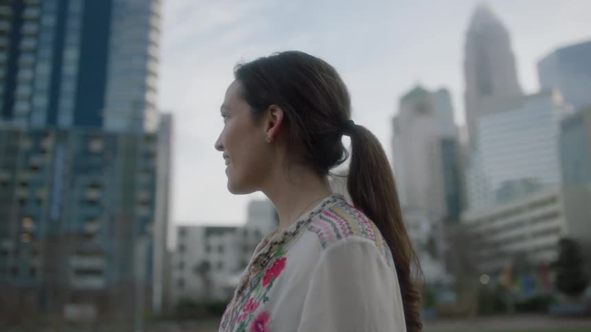 Woman stands outside looking at skyscrapers