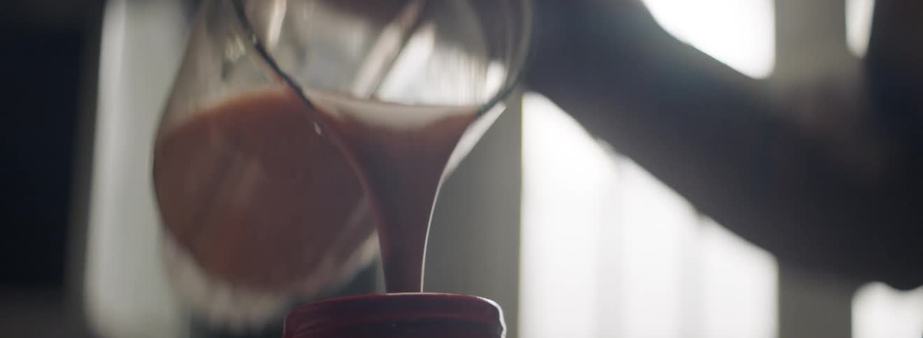 A man pours liquid from a blender into a canister