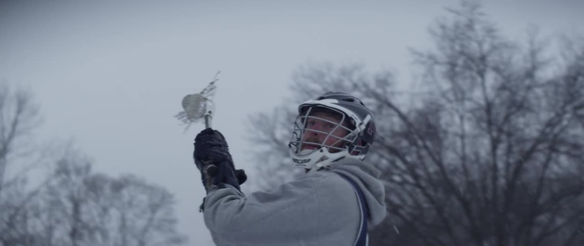 Man launches ball out of lacrosse stick on a cloudy day