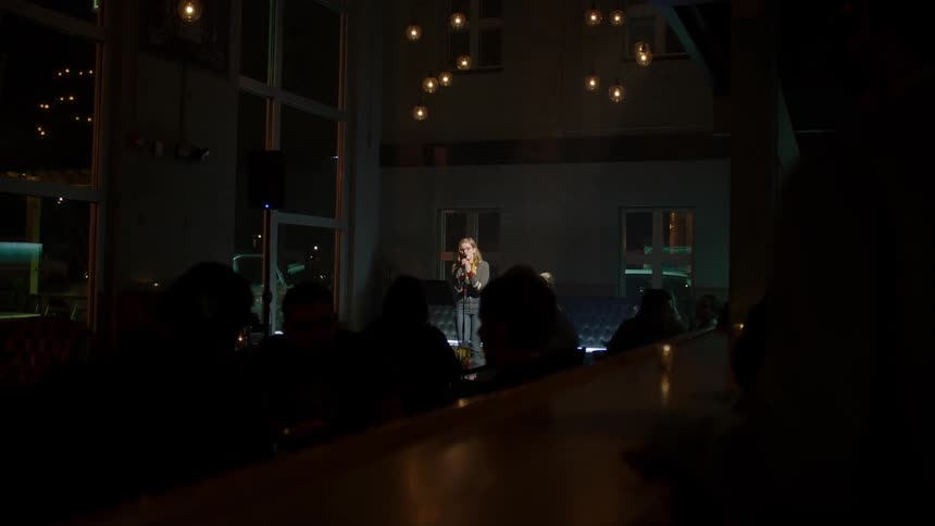 Woman sings on stage in front of an audience