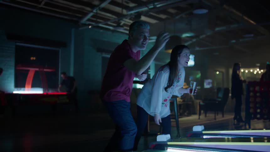 A man and woman are tossing balls in an arcade