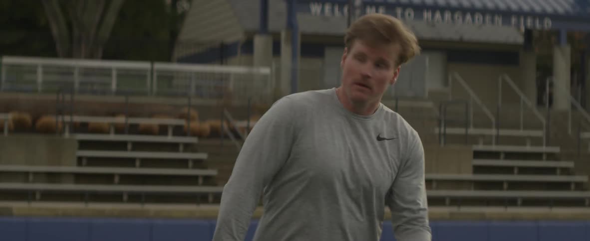 Man with lacrosse net flings a ball in stadium