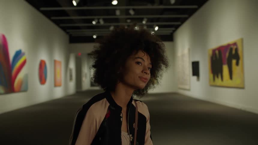 A woman is looking at art in a hall